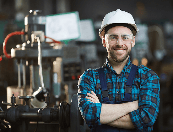 Worker in industrial setting wearing hard hat and safety glasses